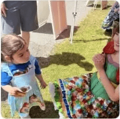 A toddler in costume beside a Happily Ever Laughter performer in a floral dress outdoors.