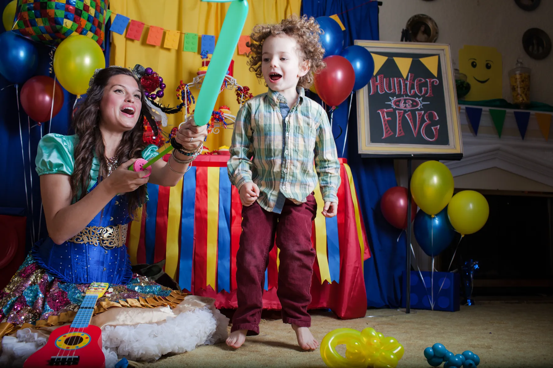 A HELP Faerie playing balloon swords with a laughing child at a birthday party.