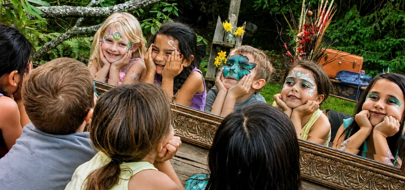 A child delighted by their finished face-paint transformation.
