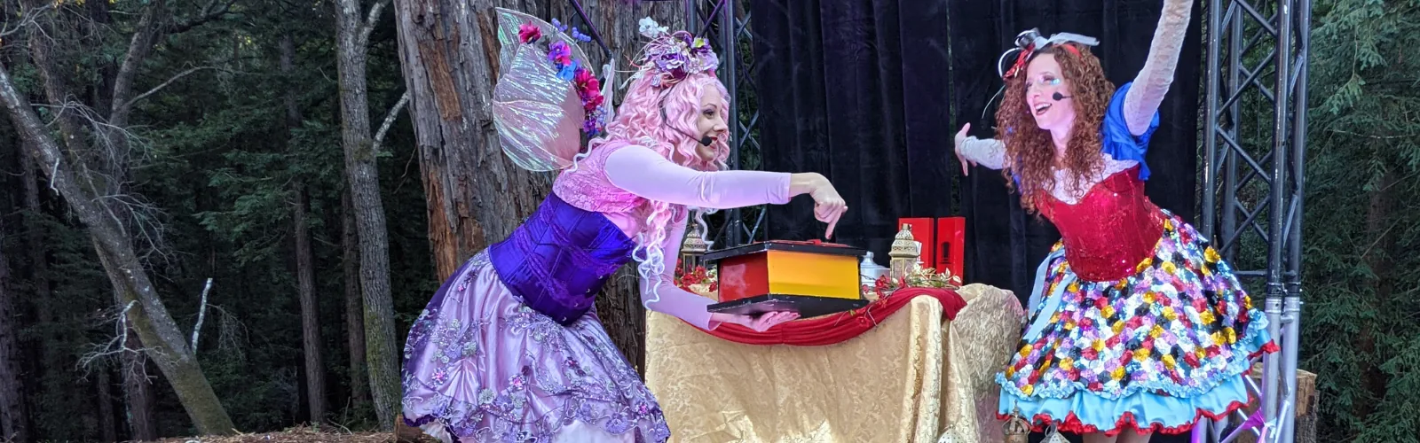 Costumed performers entertaining children with games and balloon animals at an outdoor company event.