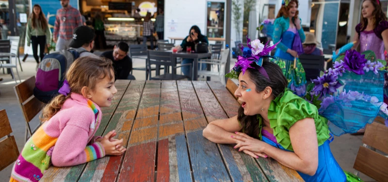 A performer entertaining children at their table during a restaurant family night.