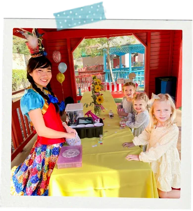 A child at a party proudly holding up a craft they made with a Happily Ever Laughter craft leader.