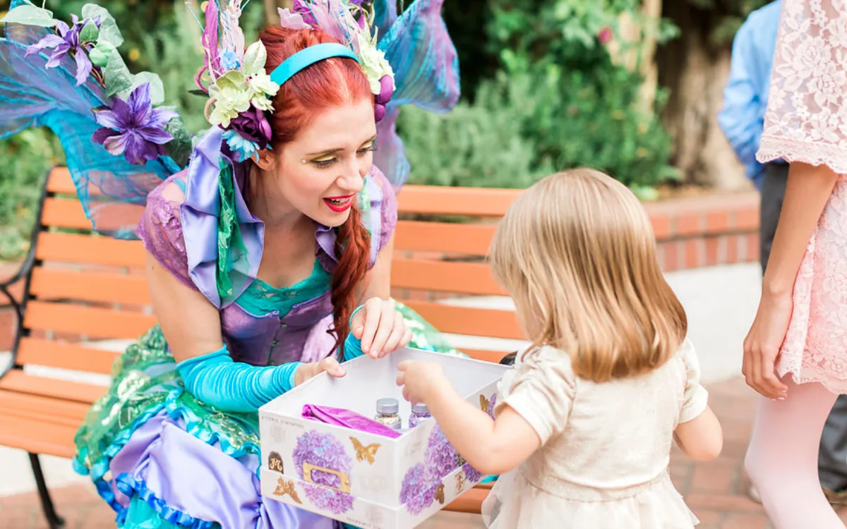 A Happily Ever Laughter craft leader roaming an outdoor party bringing crafts to children.