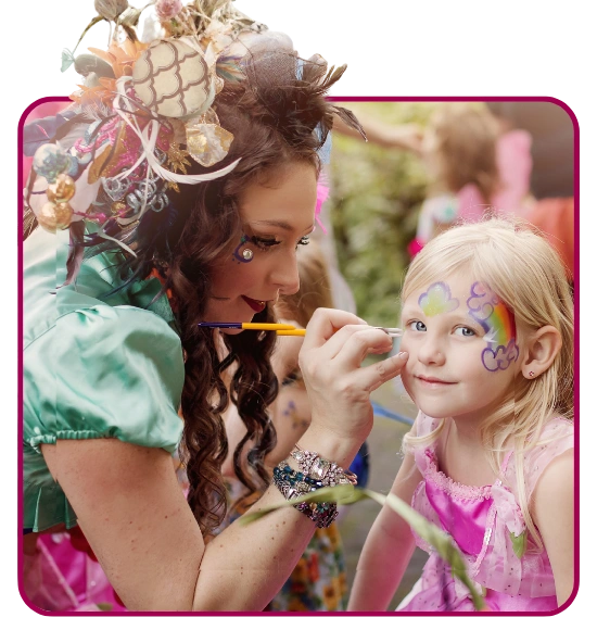 A Happily Ever Laughter face painter applying a glittery design to a child's face outdoors.