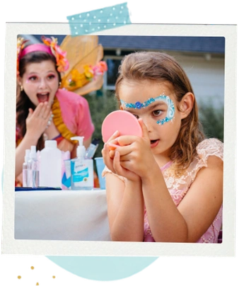 A child at a party holding a hand mirror to admire her freshly painted face.
